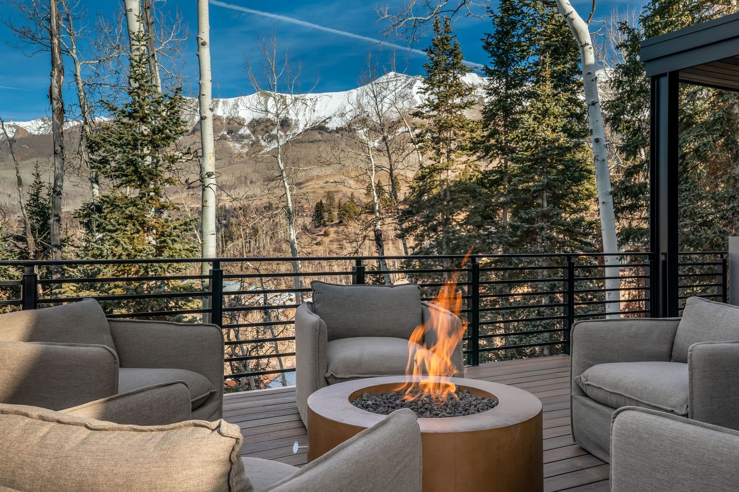Outdoor deck seating area with fire pit and mountain views through cable railing.