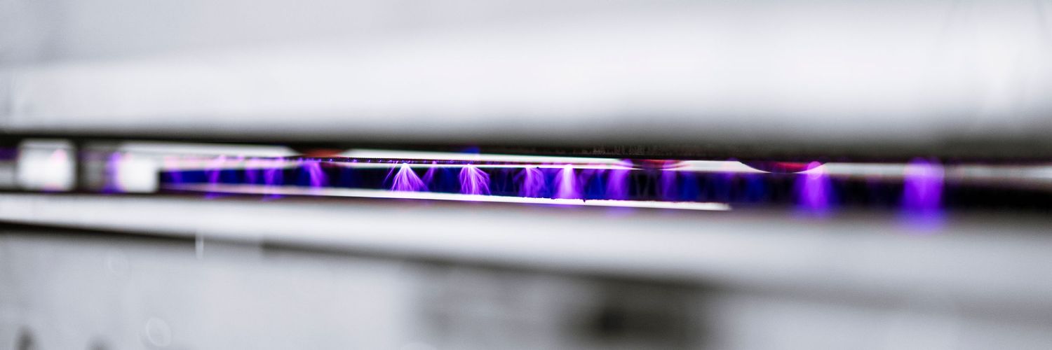 Blurred close-up view of purple LED lights glowing along a sleek metallic surface.