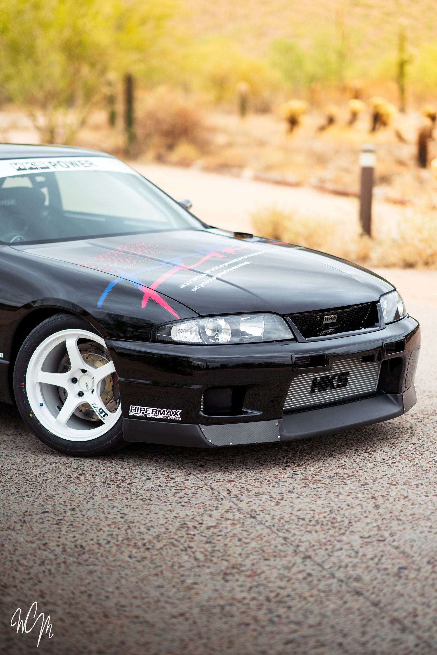 Close-up shots of a sleek black RC drift car model with white wheels on asphalt ground in dramatic angles.