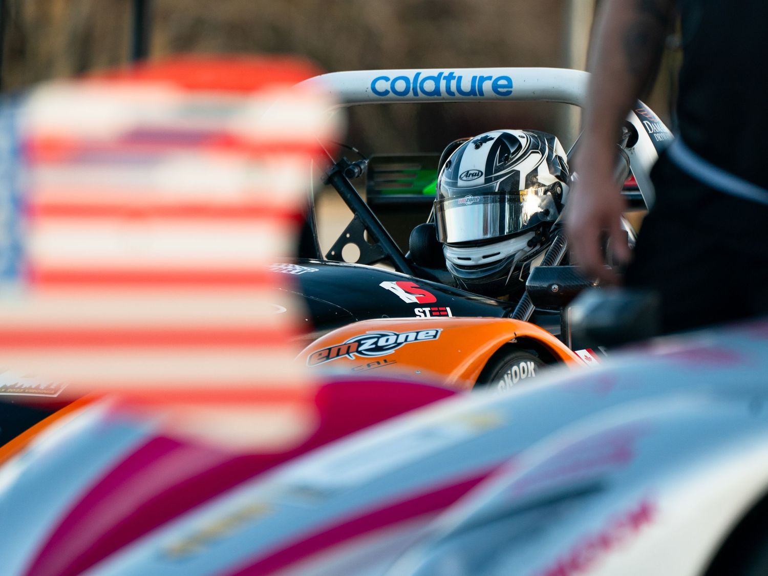 Race car detail with American flag reflections visible in the paintwork.