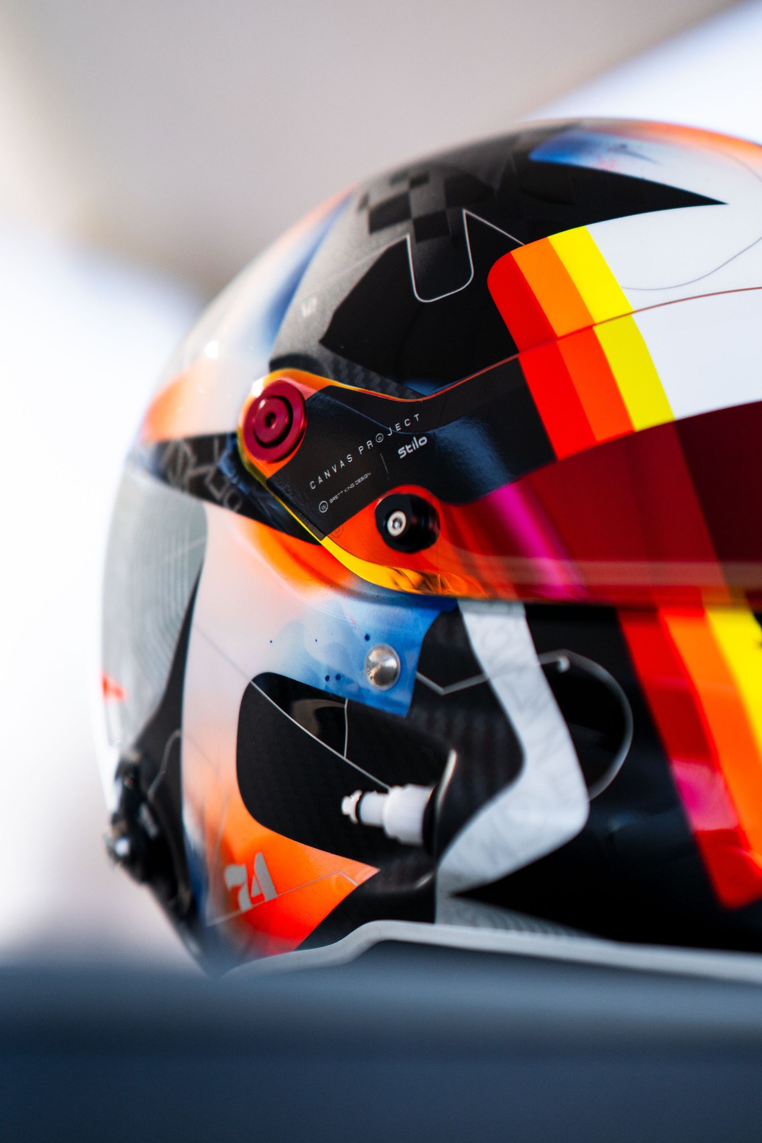 Close-up view of a racing helmet with black, red, and yellow stripes showing reflective visor details.