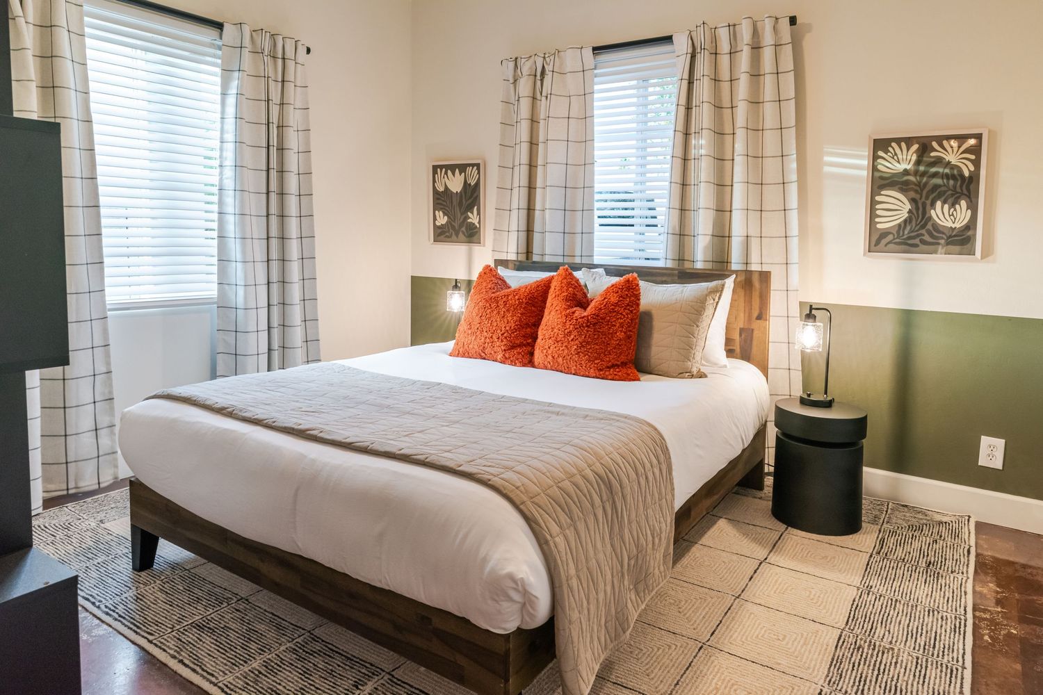 Modern bedroom interior with plush bedding, striped curtains, and orange accent pillows.
