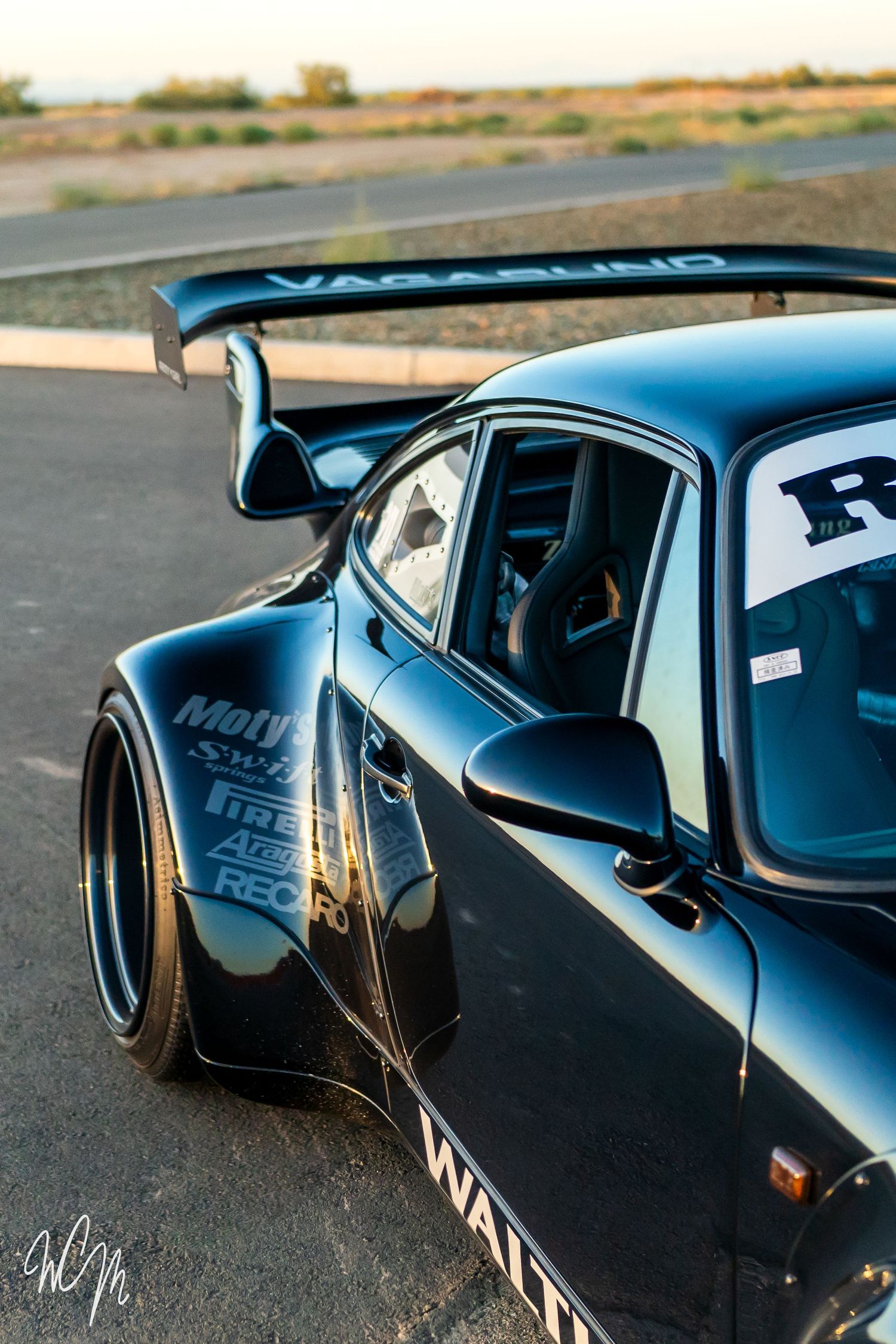 Close-up detail of black Porsche 911's wide body kit and racing modifications.