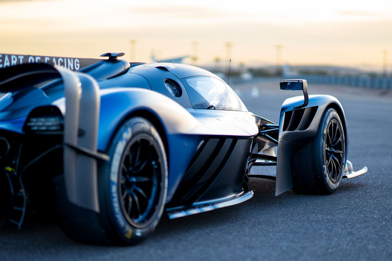 Side profile of modern racing cars showcasing aerodynamic design features at dusk.