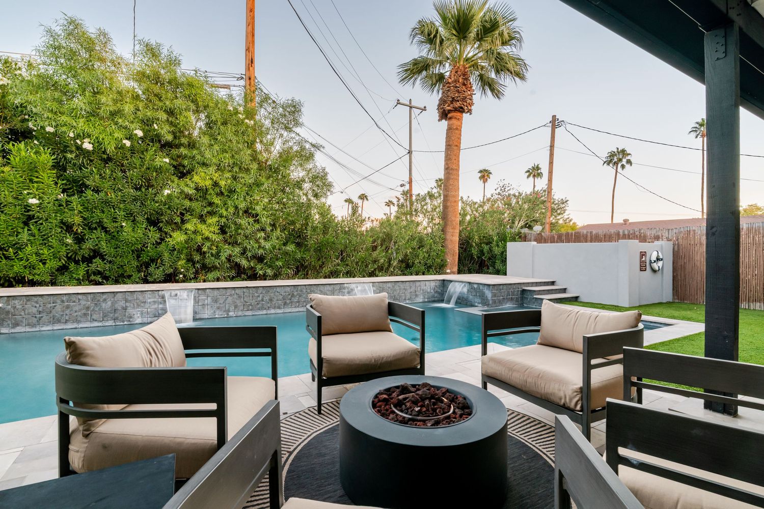 Modern outdoor patio area with comfortable seating and palm trees creating a relaxing desert oasis atmosphere.