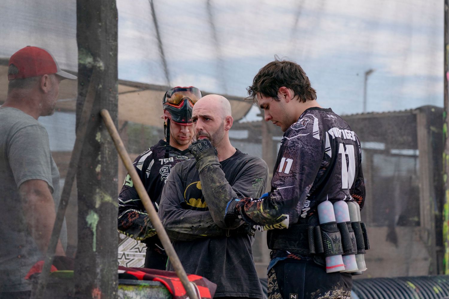 Paintball players discussing strategy between matches on field.