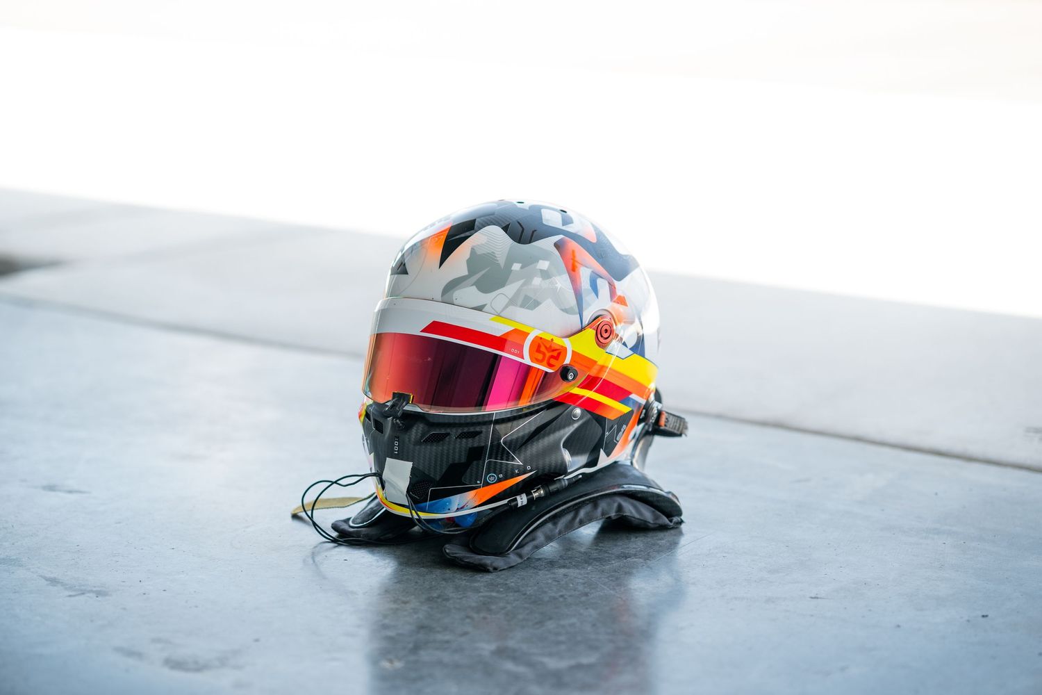 Racing helmets arranged in a row on a white surface showing various team colors and designs.