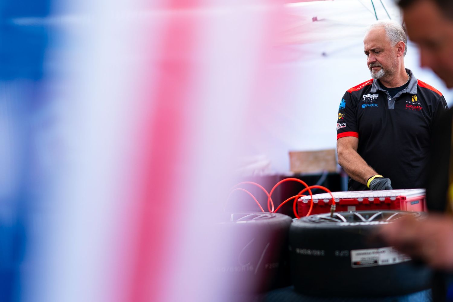 Racing team members working on equipment preparations in a garage setting.