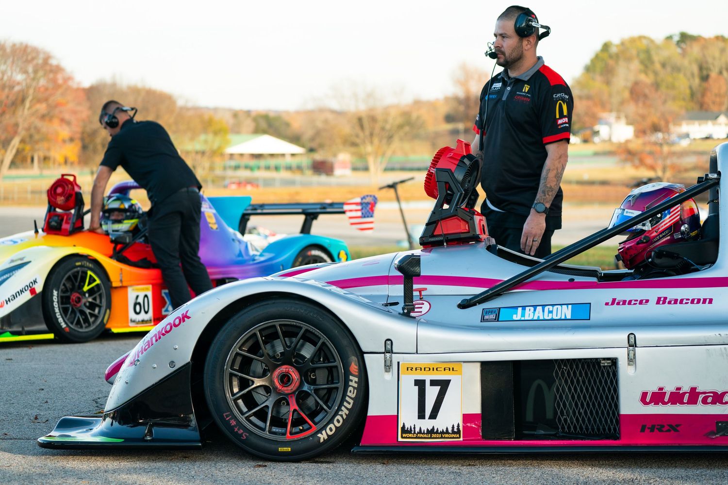 Multiple race cars lined up on track with colorful liveries and racing slick tires.