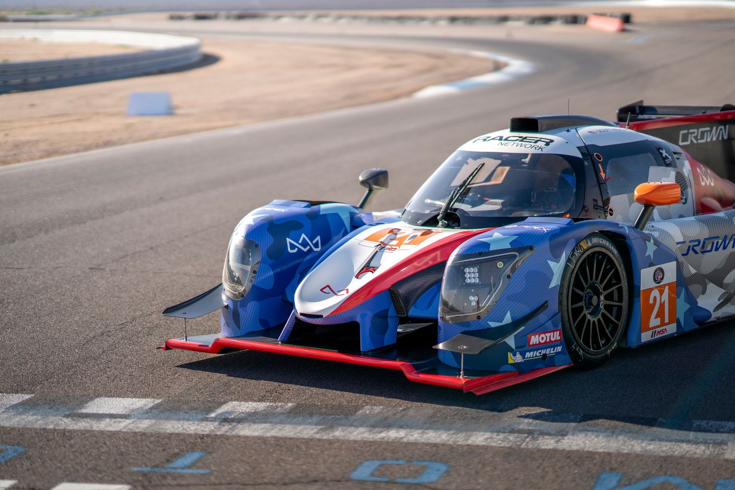 Patriotic red white and blue LMP2 race car on track with number 21.