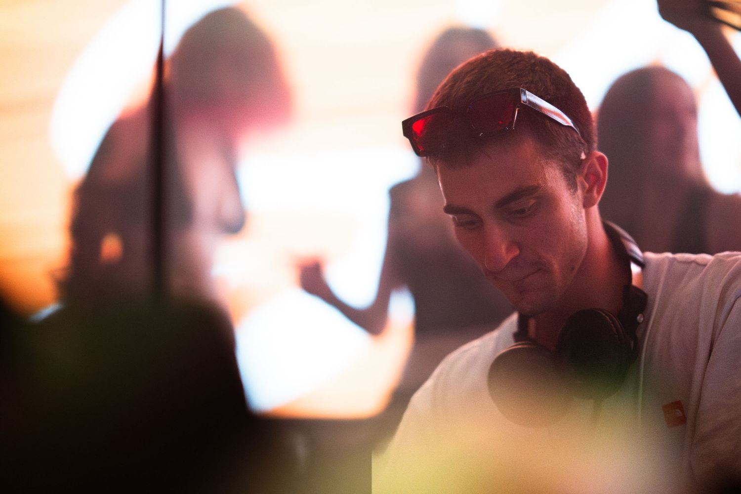 A person sits at a bar counter in dim lighting with a blurred background creating an atmospheric mood.