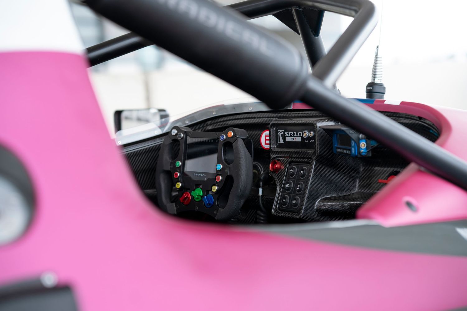 Close-up view of black steering wheel controls and pink interior trim details of a modern vehicle.