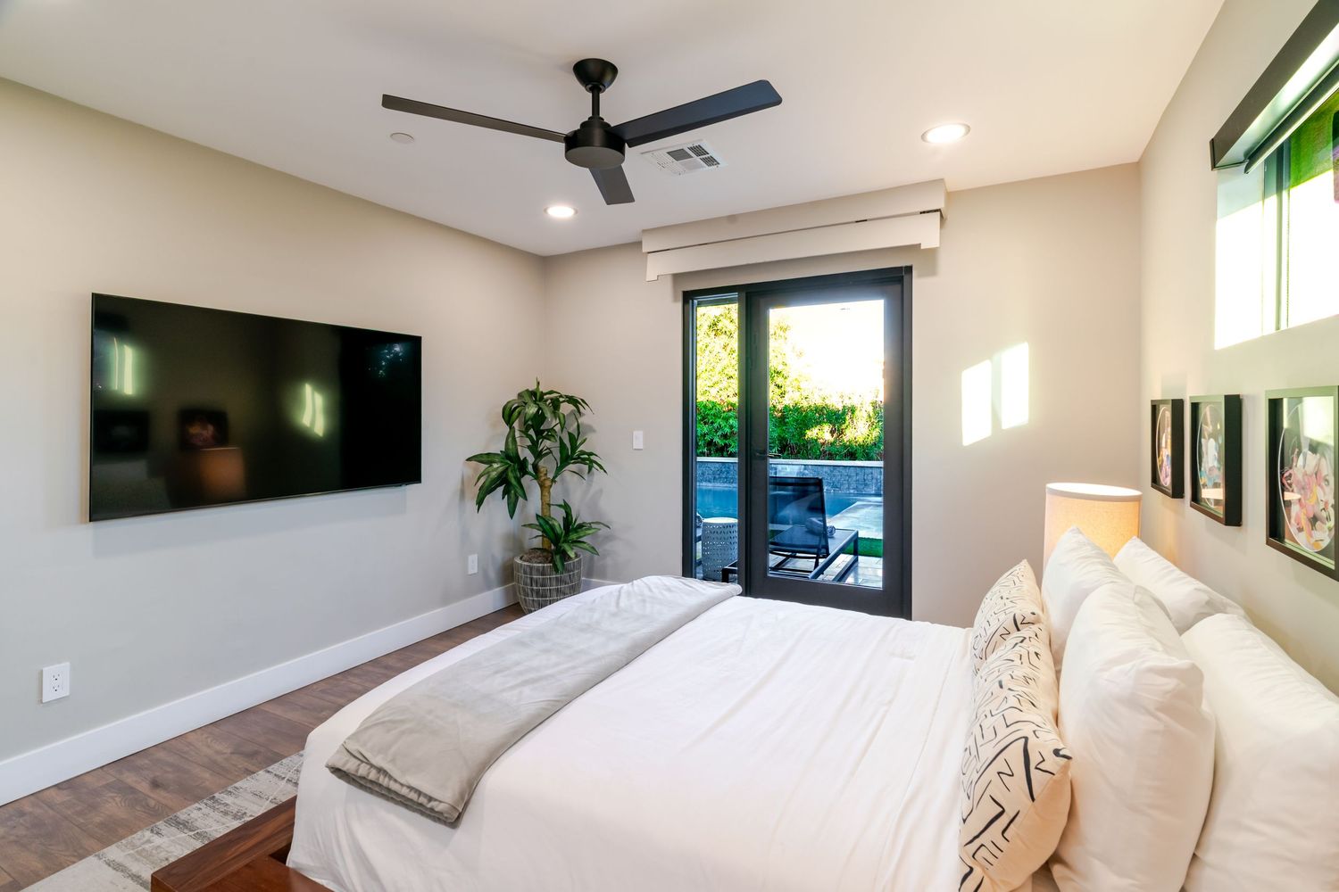 Minimalist bedroom design with high ceilings, ceiling fan, and large windows for natural light.