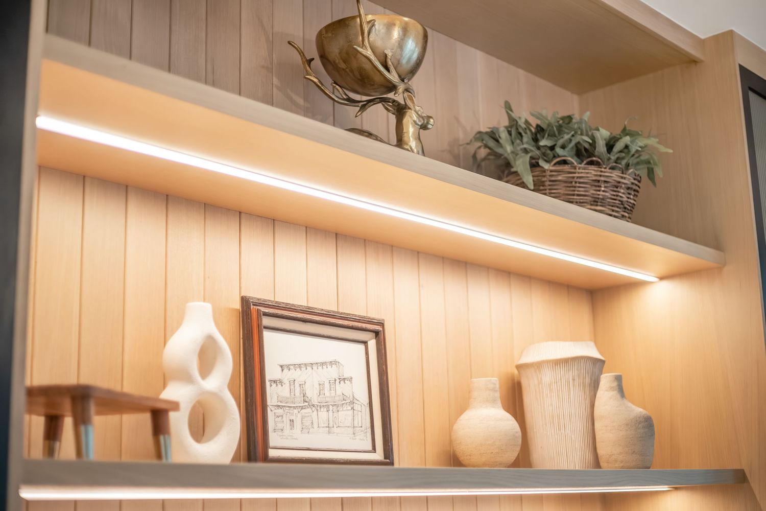 Modern farmhouse kitchen features white shiplap walls, floating wooden shelves, and decorative pottery displays.