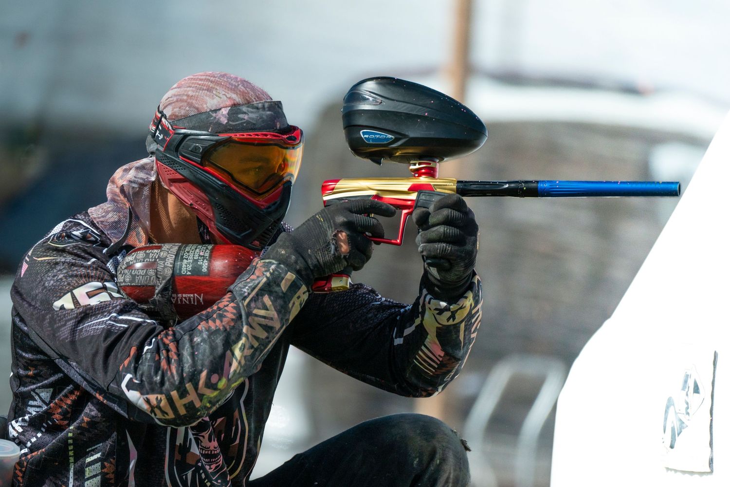 Paintball players in protective gear crouch behind obstacles during an intense competitive match.