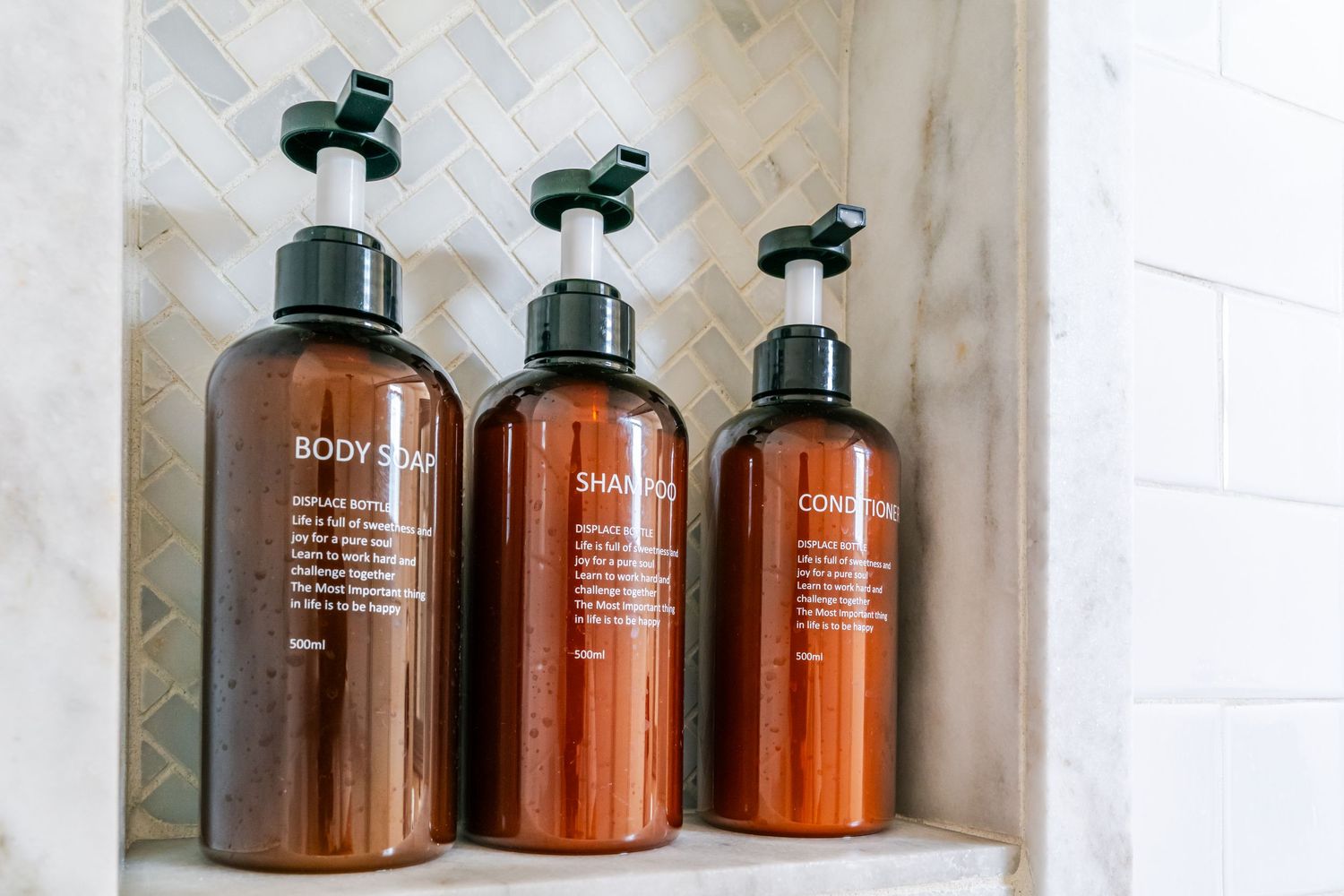 Amber glass bathroom bottles arranged neatly on white shelving with minimalist aesthetic.
