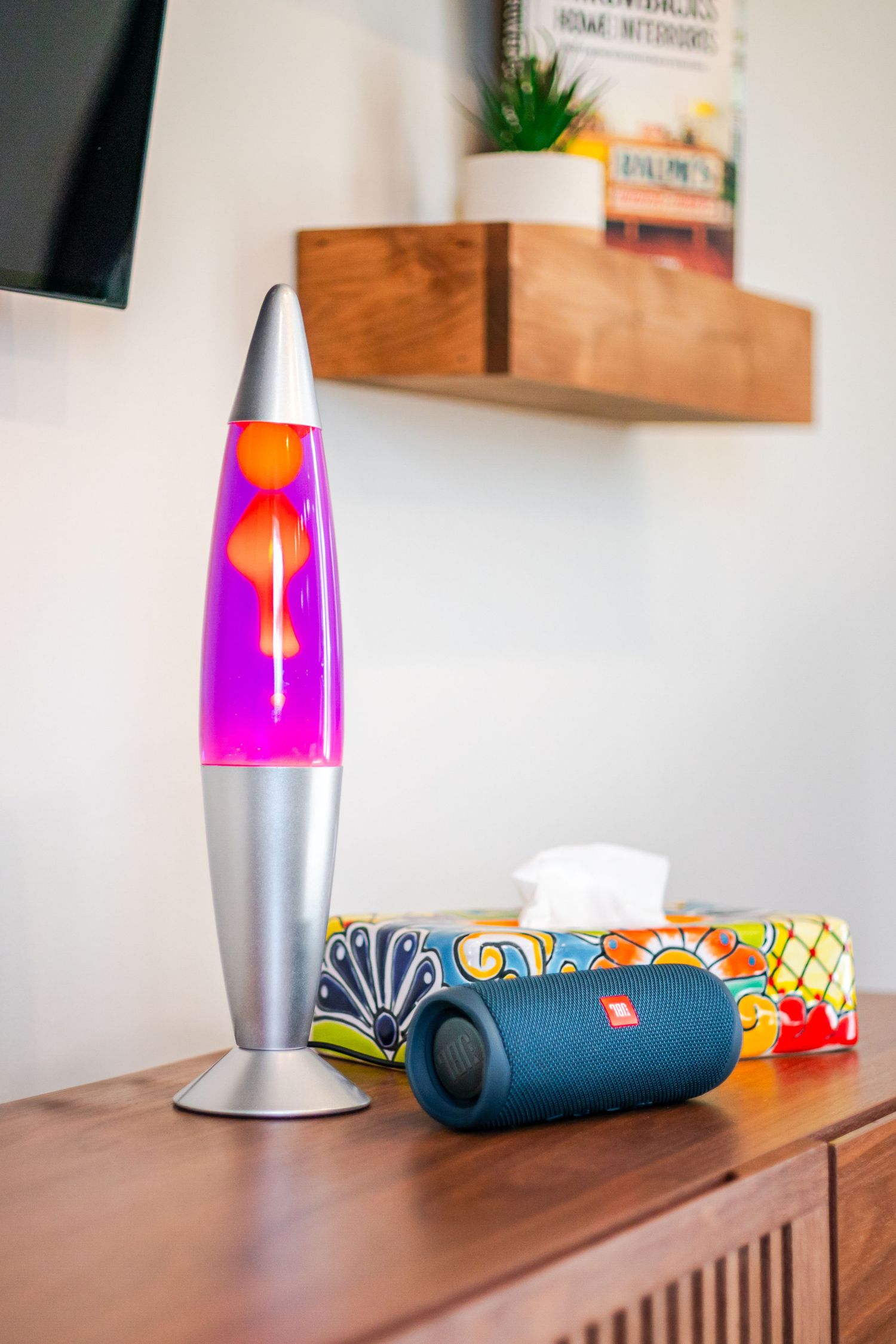 Retro-style lava lamp in pink and purple colors displayed on a wooden surface with decorative items.