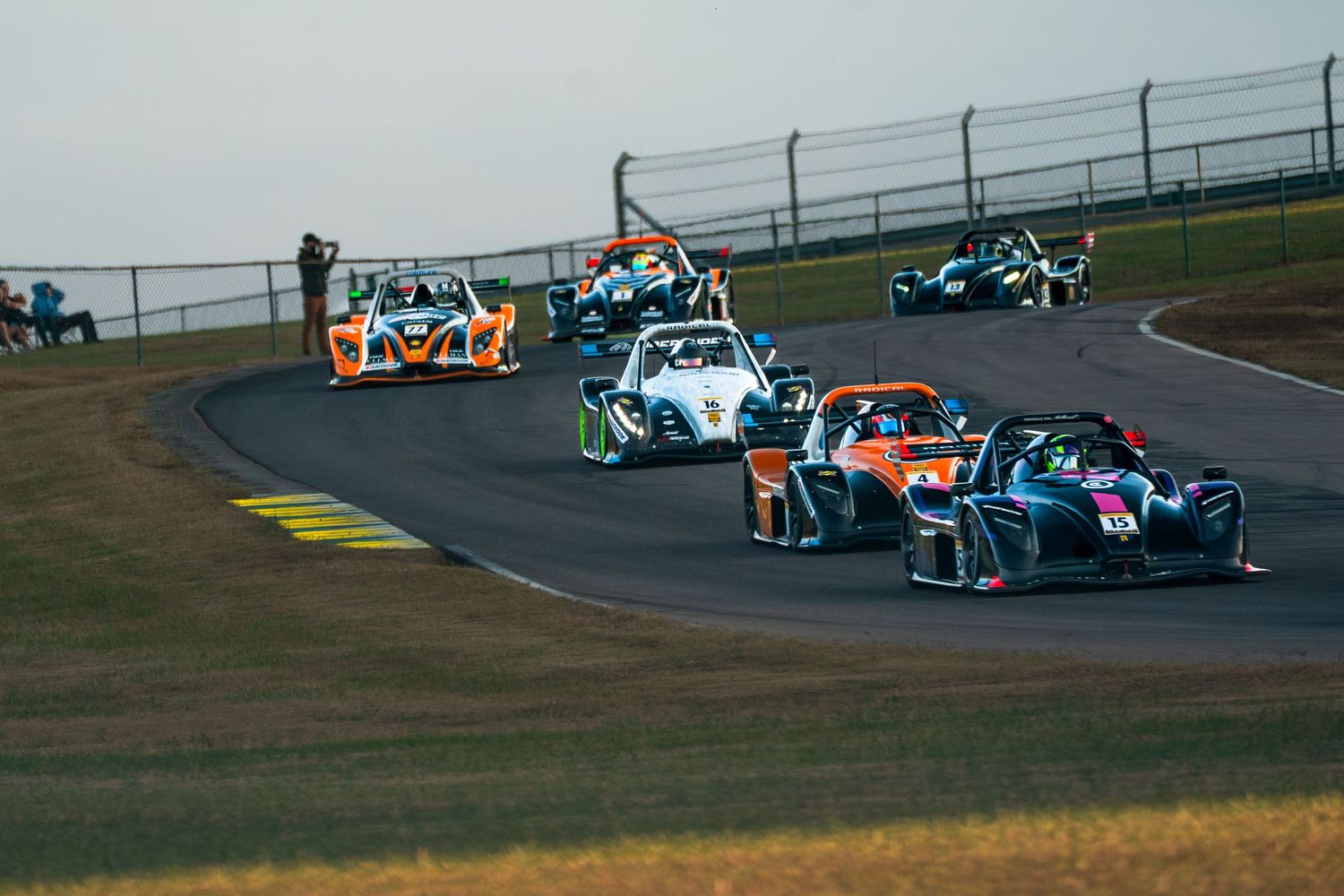 Multiple race cars competing through a curved section of the racing circuit.