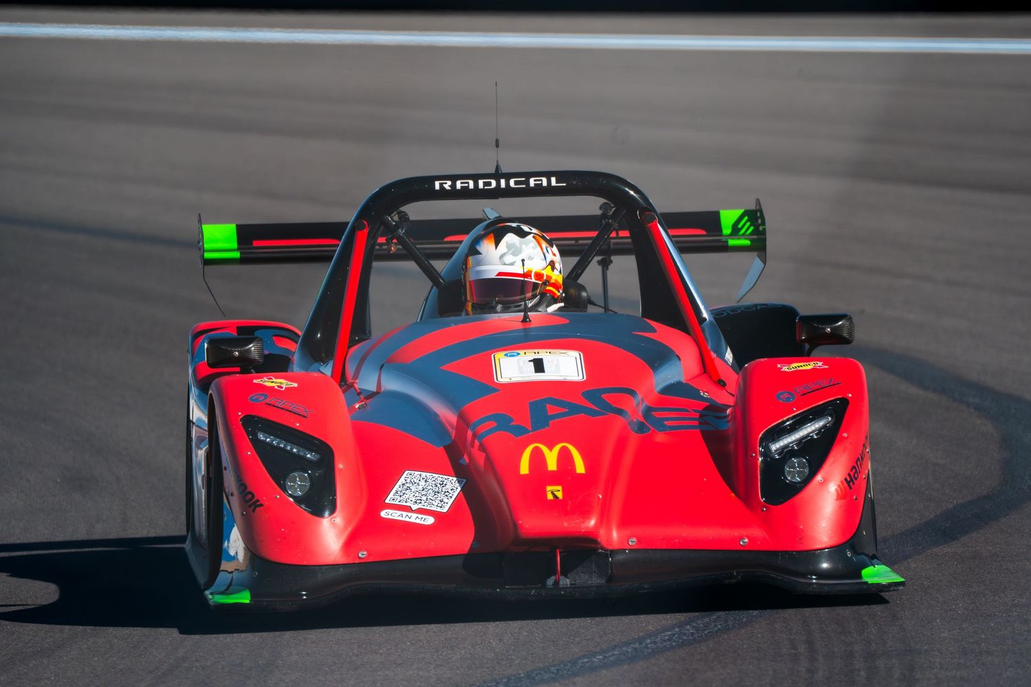 Red racing cars compete on a racetrack during a professional motorsport competition.