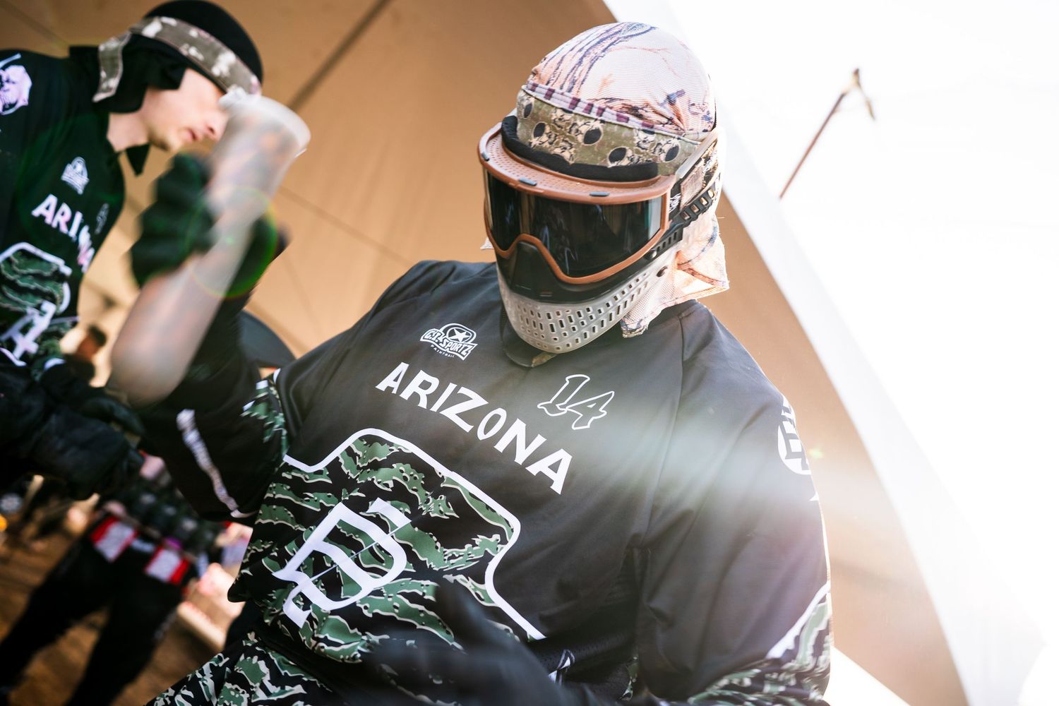 Arizona paintball player wearing protective helmet, goggles, and team jersey number 14 during a competitive match.