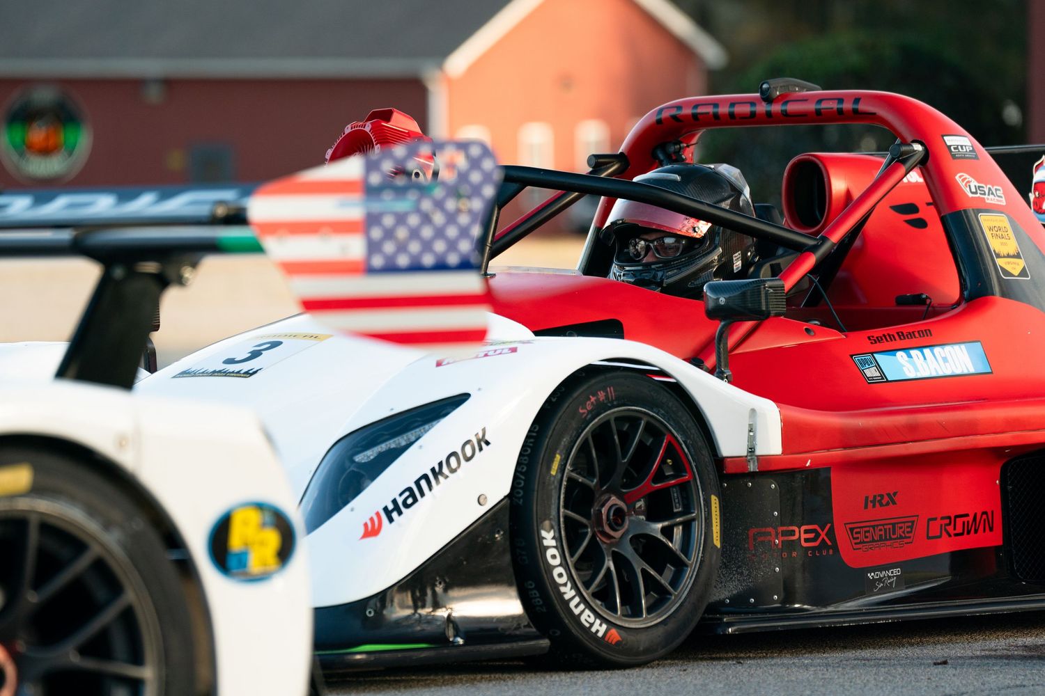 Formula-style race cars lined up on track with red and white livery.