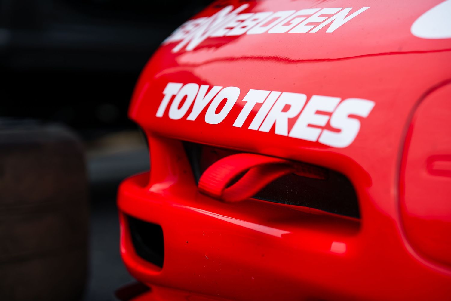 Close-up of a red race car hood featuring Toyo Tires and Neoogen sponsor decals.