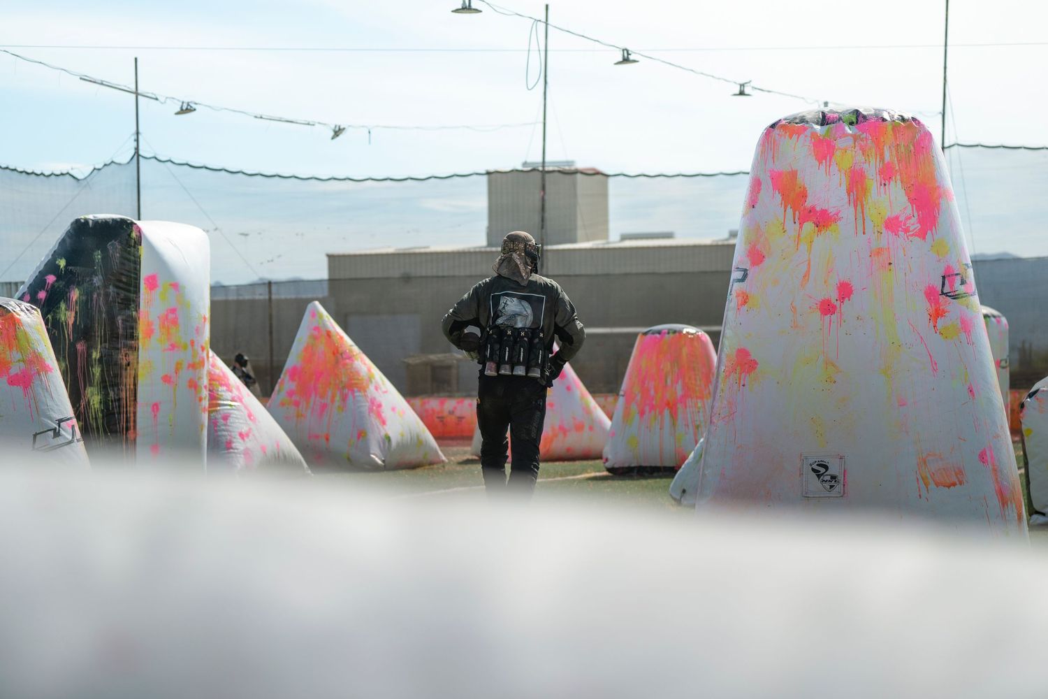 Paintball field setup with colorful inflatable bunkers and pink paint splatters.