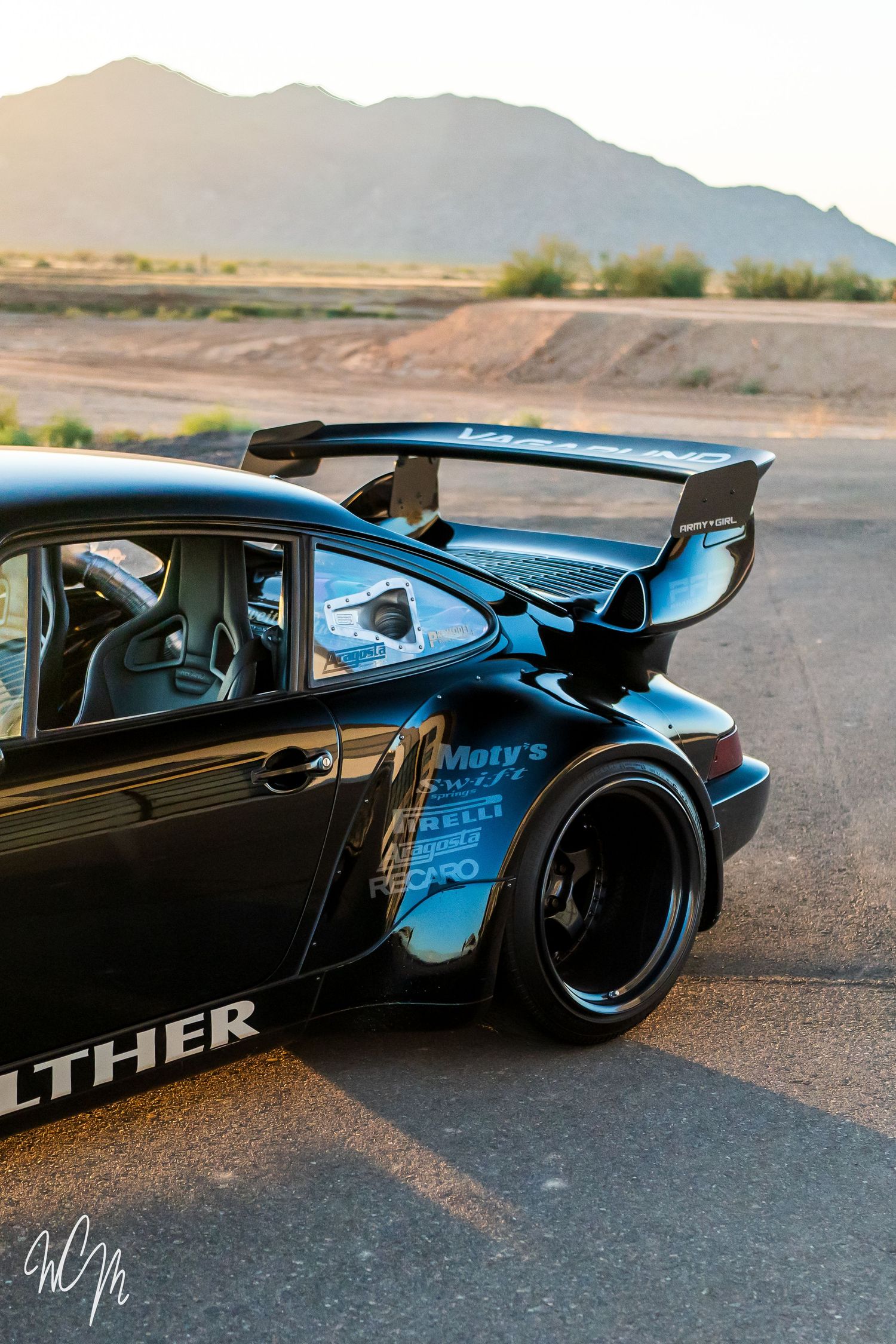 Rear quarter view of modified Porsche 911 showing massive wing and wide body kit.