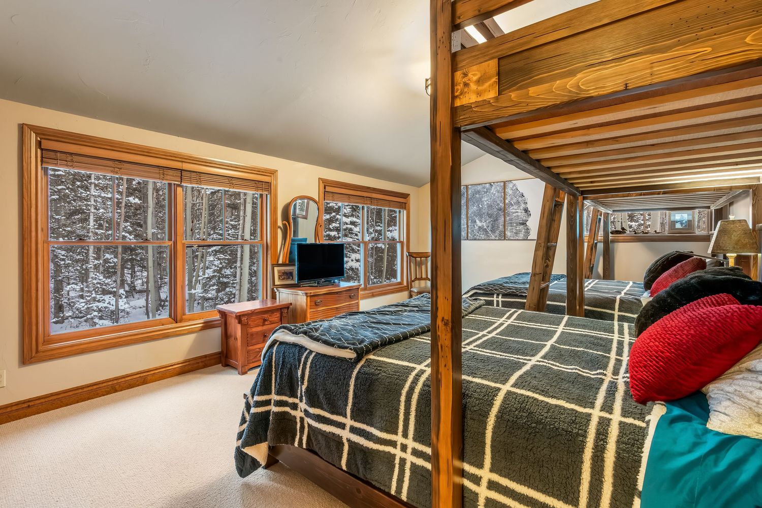 Cozy bunk beds with dark green bedding arranged in a wood-paneled room with natural lighting.