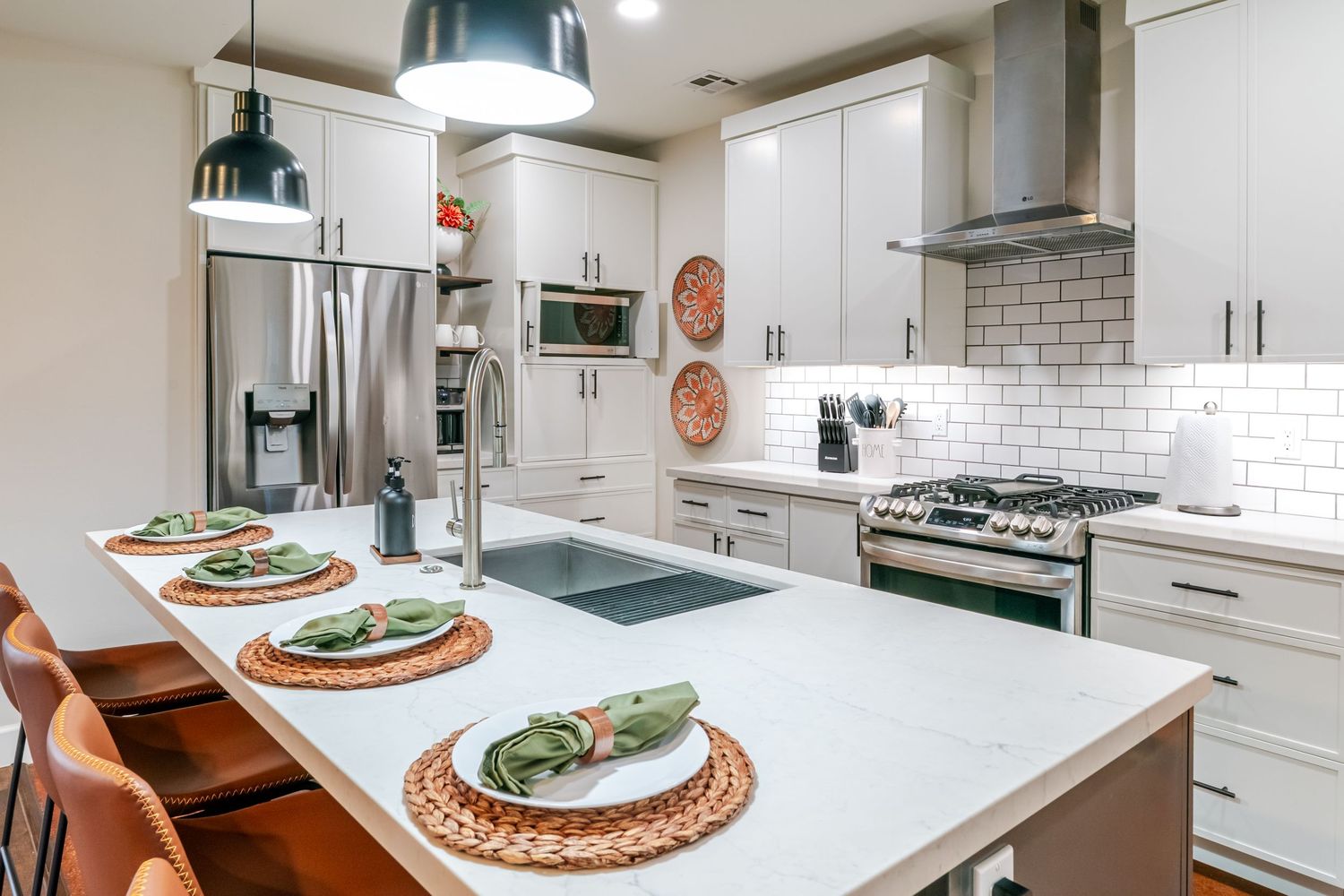 Contemporary white kitchen with subway tile backsplash, stainless appliances, and pendant lighting.