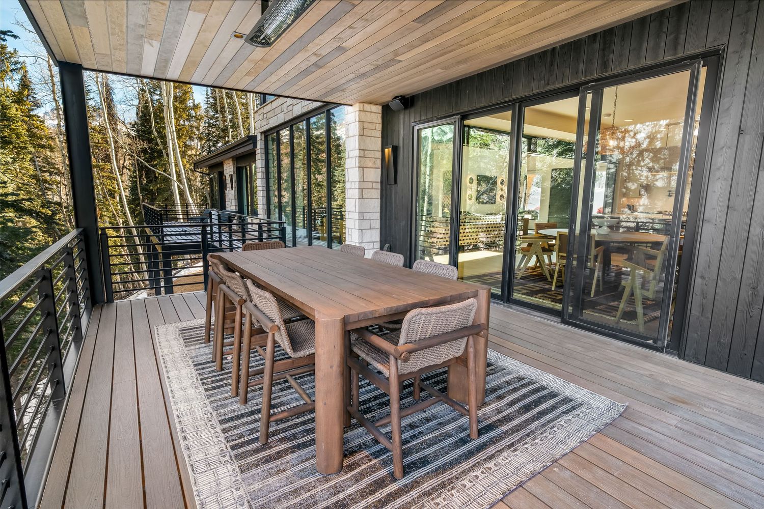 Modern outdoor deck with wooden flooring and glass railings showcases stunning mountain views and contemporary seating areas.