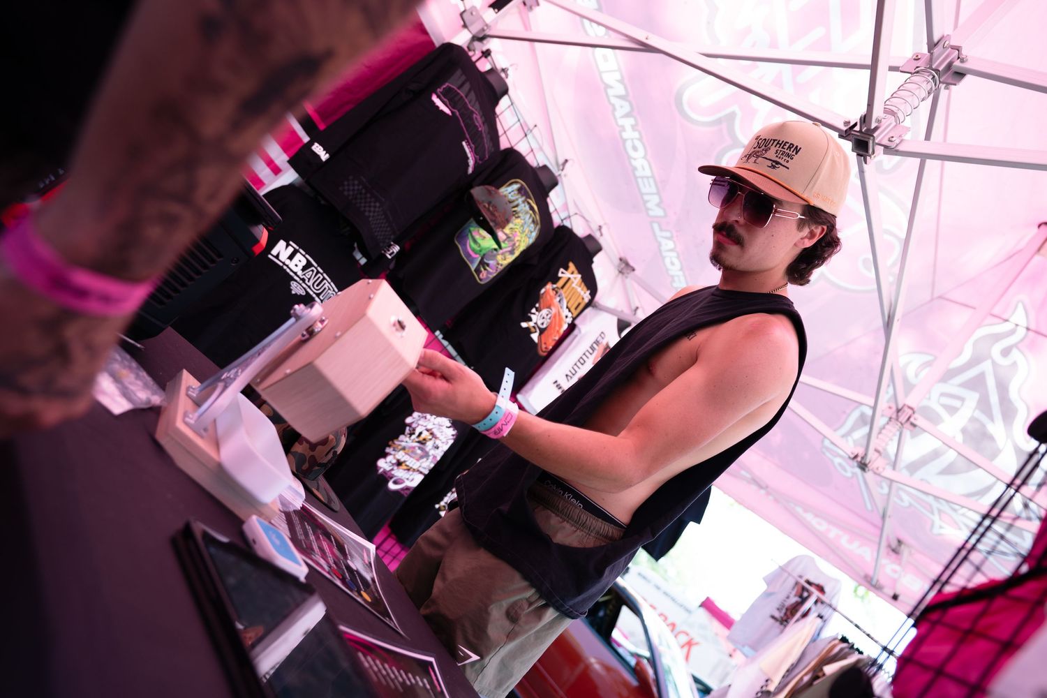 Young vendor operating a point-of-sale system at a merchandise booth during an outdoor event.