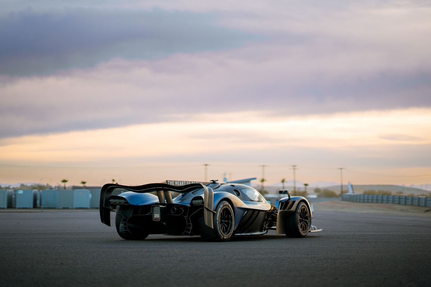 Dramatic wide angle view of performance vehicles on a desert racetrack at sunset.