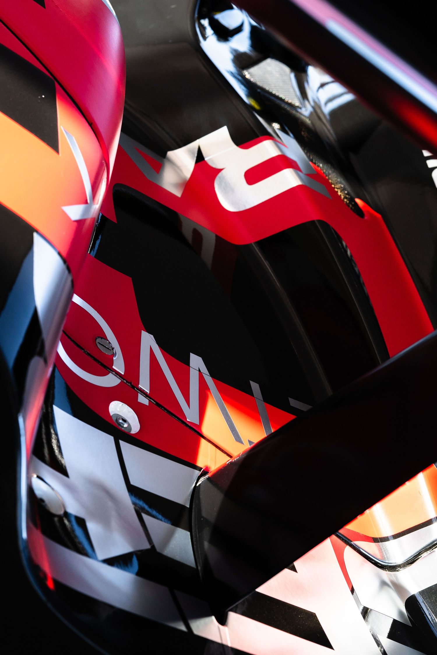 Abstract close-up of racing car bodywork showing red and white geometric patterns.