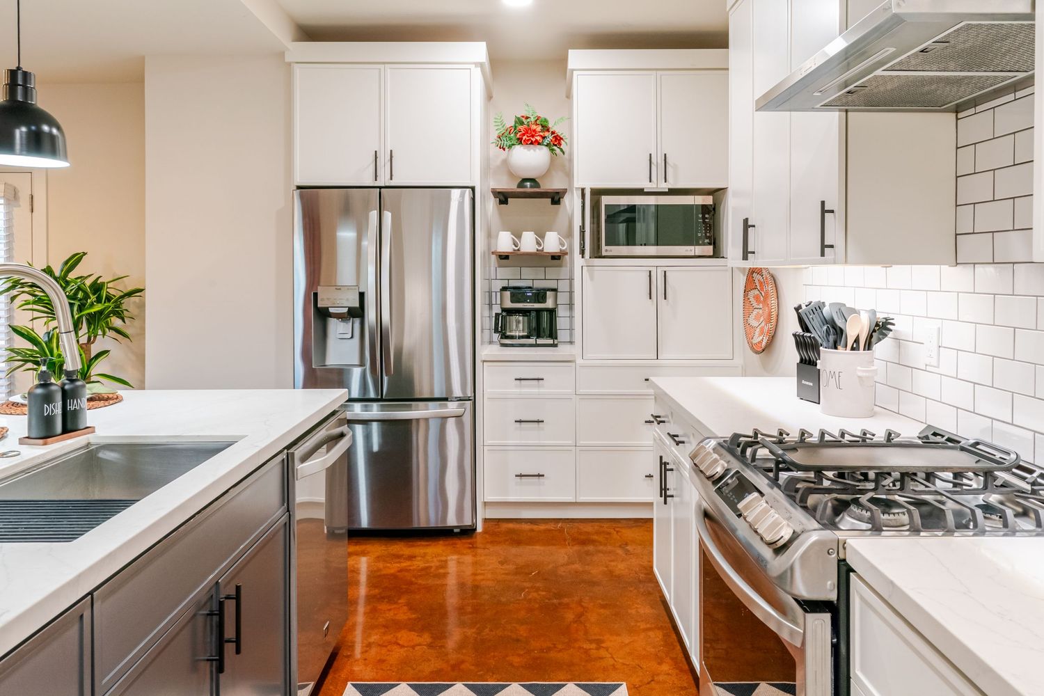 Modern white kitchen with subway tile backsplash, stainless appliances, and wood flooring.