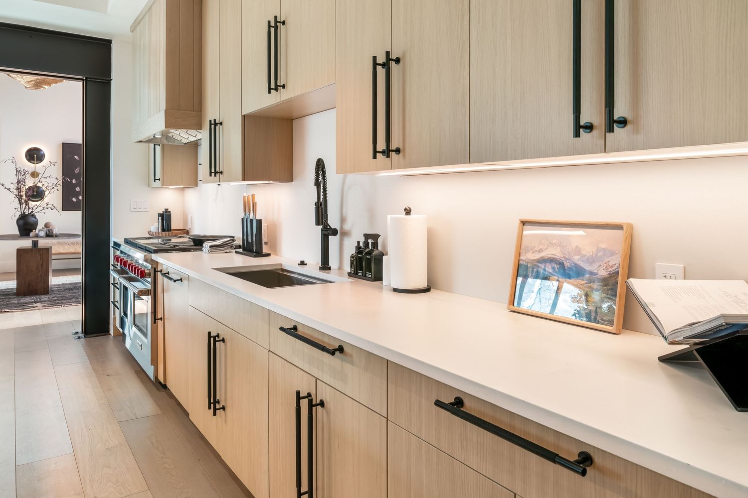 Contemporary kitchen interior featuring sleek cabinetry, black hardware, and under-cabinet lighting in a linear layout.