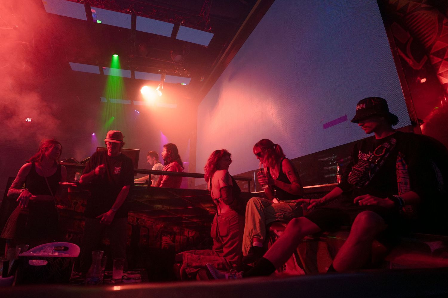 People enjoying a live music performance in a dimly lit venue with dramatic red lighting effects.