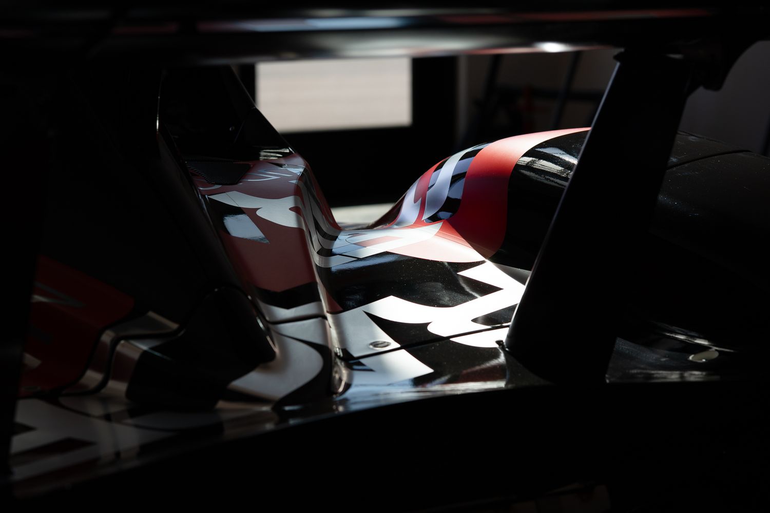 Shadowy interior view of race car cockpit showing partial bodywork details.