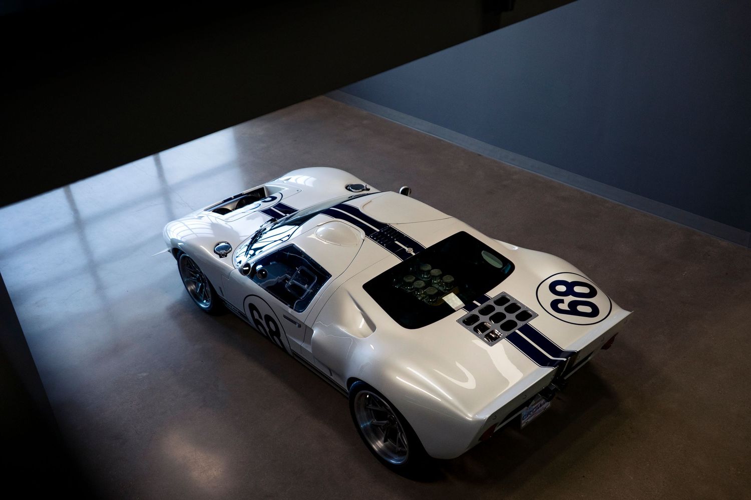 Sleek white vintage racing car with number 98 displayed on its side panel in dramatic low lighting.