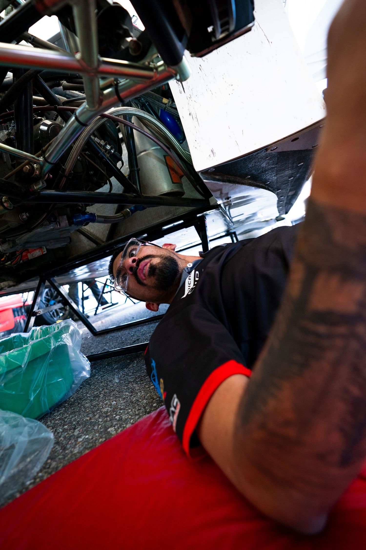 Close-up shot of a race car driver adjusting equipment in the cockpit during a motorsport event.