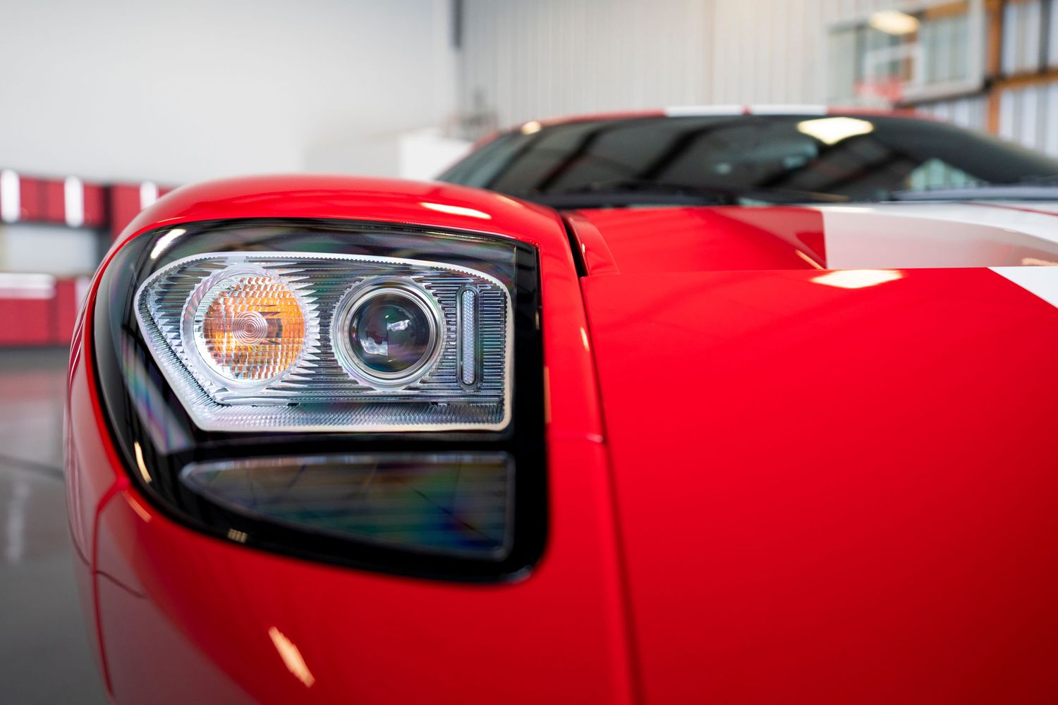 Modern headlight detail of a red sports car showing xenon projector beam.