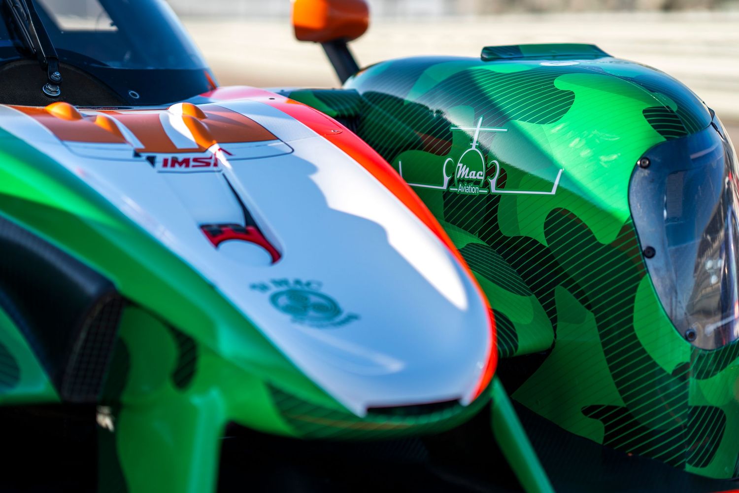 Close-up detail of green and white race car bodywork showing aerodynamic design elements.