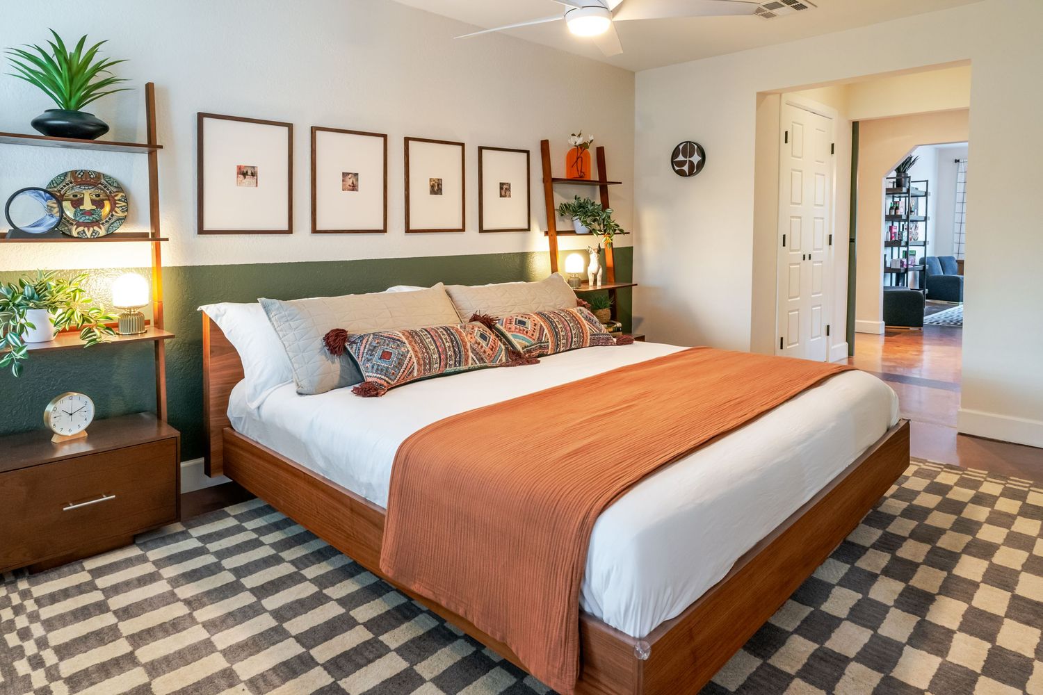 Modern bedroom with orange bedding, wood furniture, and black and white checkered flooring pattern.