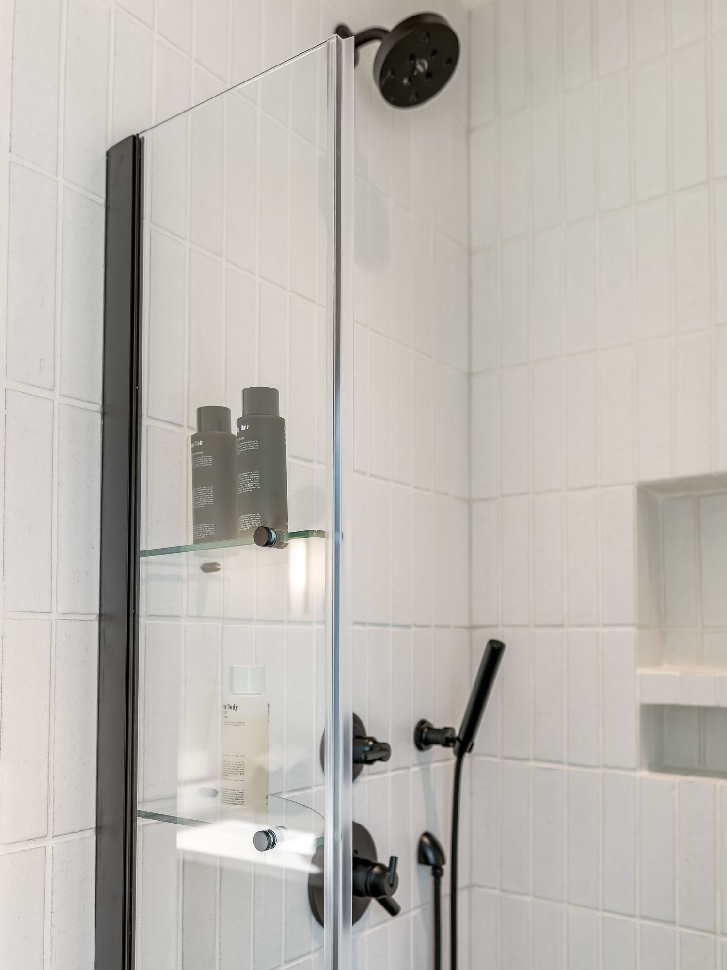 Modern bathroom interior with white subway tile walls, black fixtures, and minimalist design elements.
