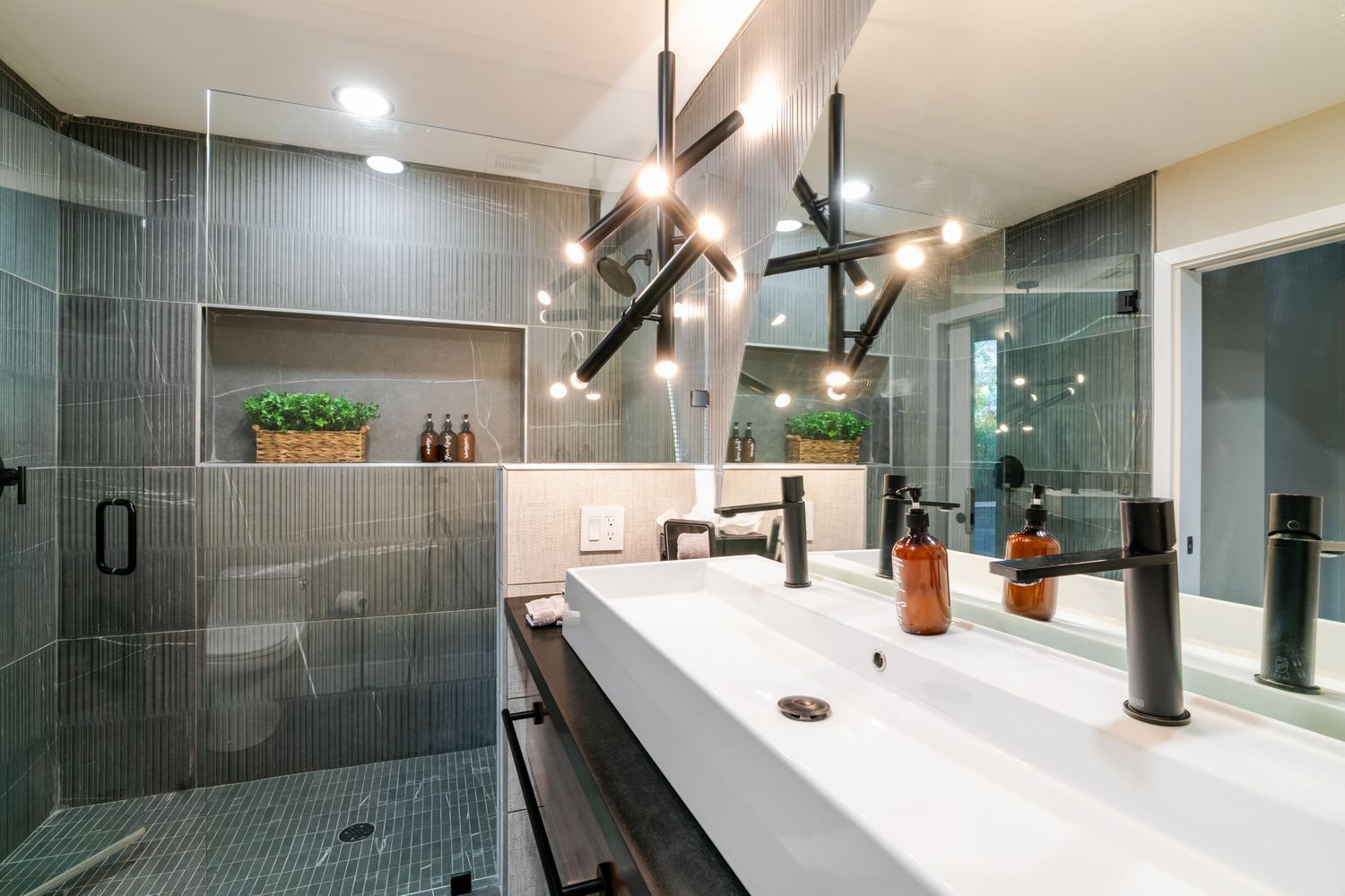 Modern bathroom interior with gray tile walls, glass shower enclosure, and recessed lighting creates a sleek spa-like atmosphere.