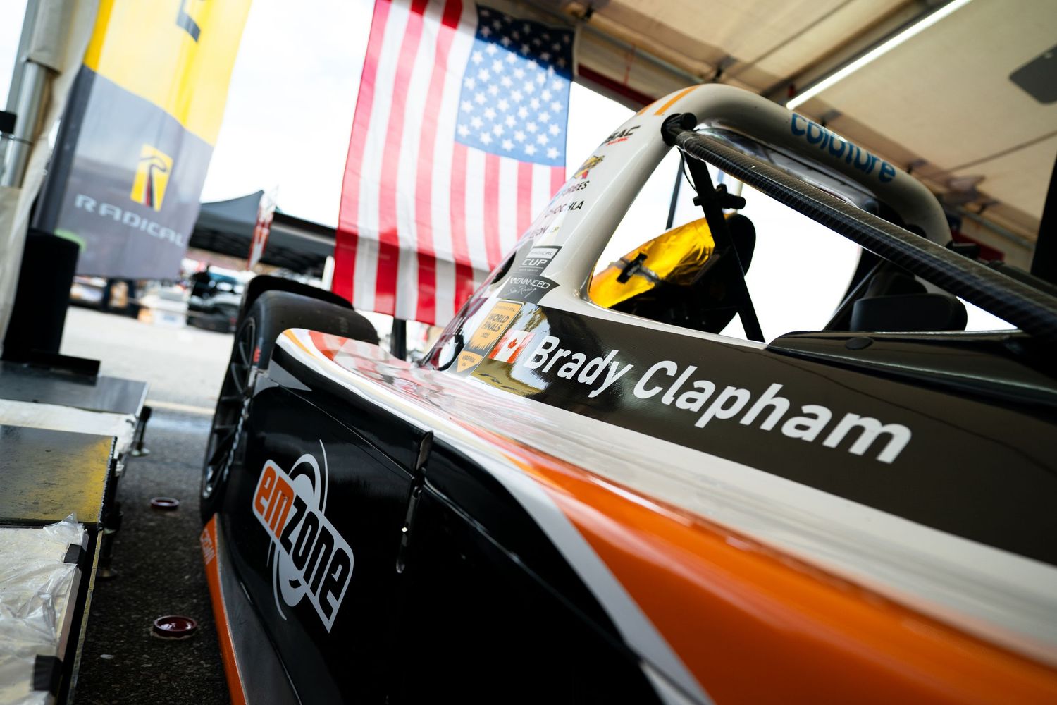 Racing car with American flag displayed in pit garage during preparation.