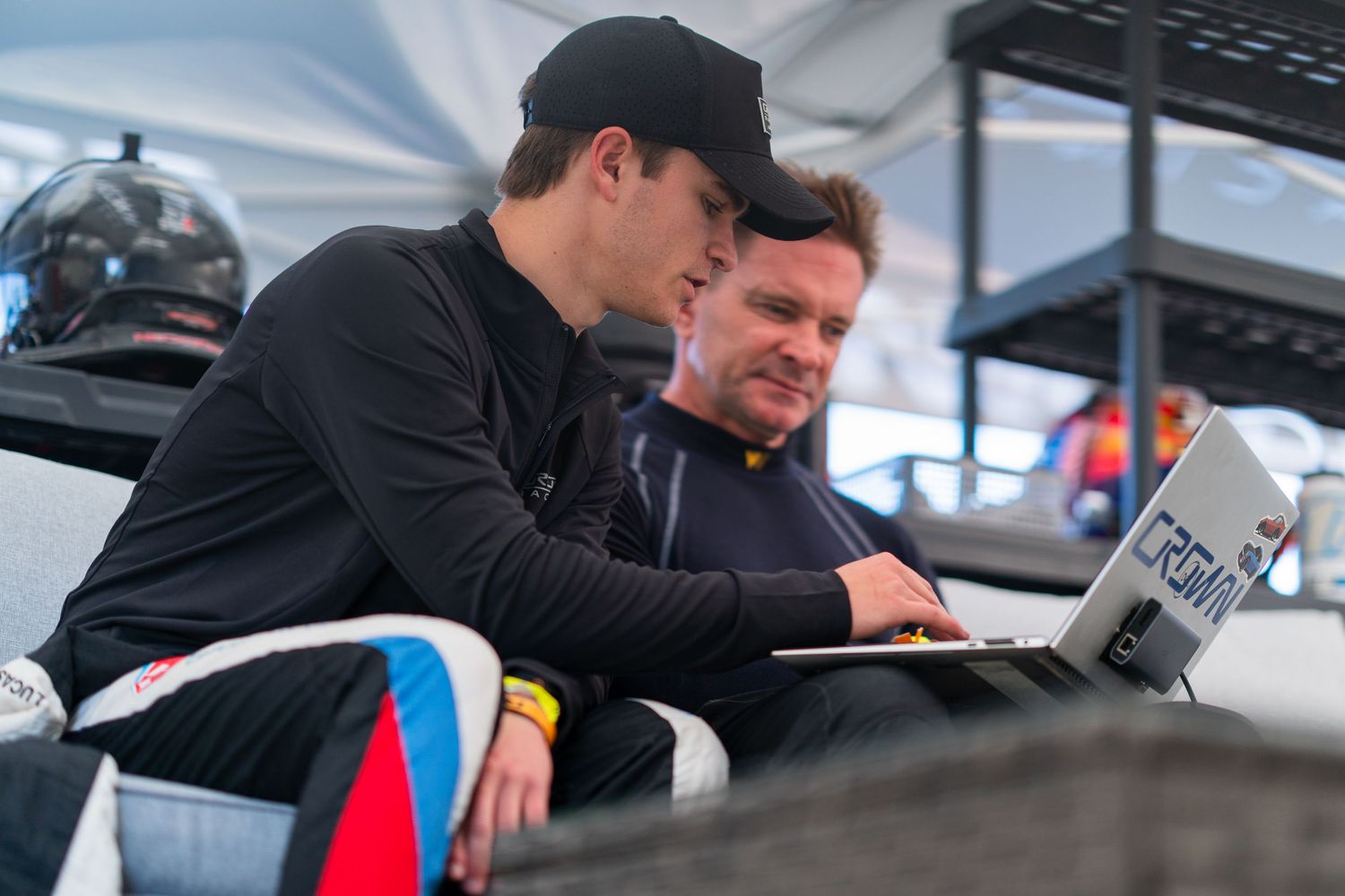Racing team members reviewing technical data and documentation in the pit garage during a motorsport event.