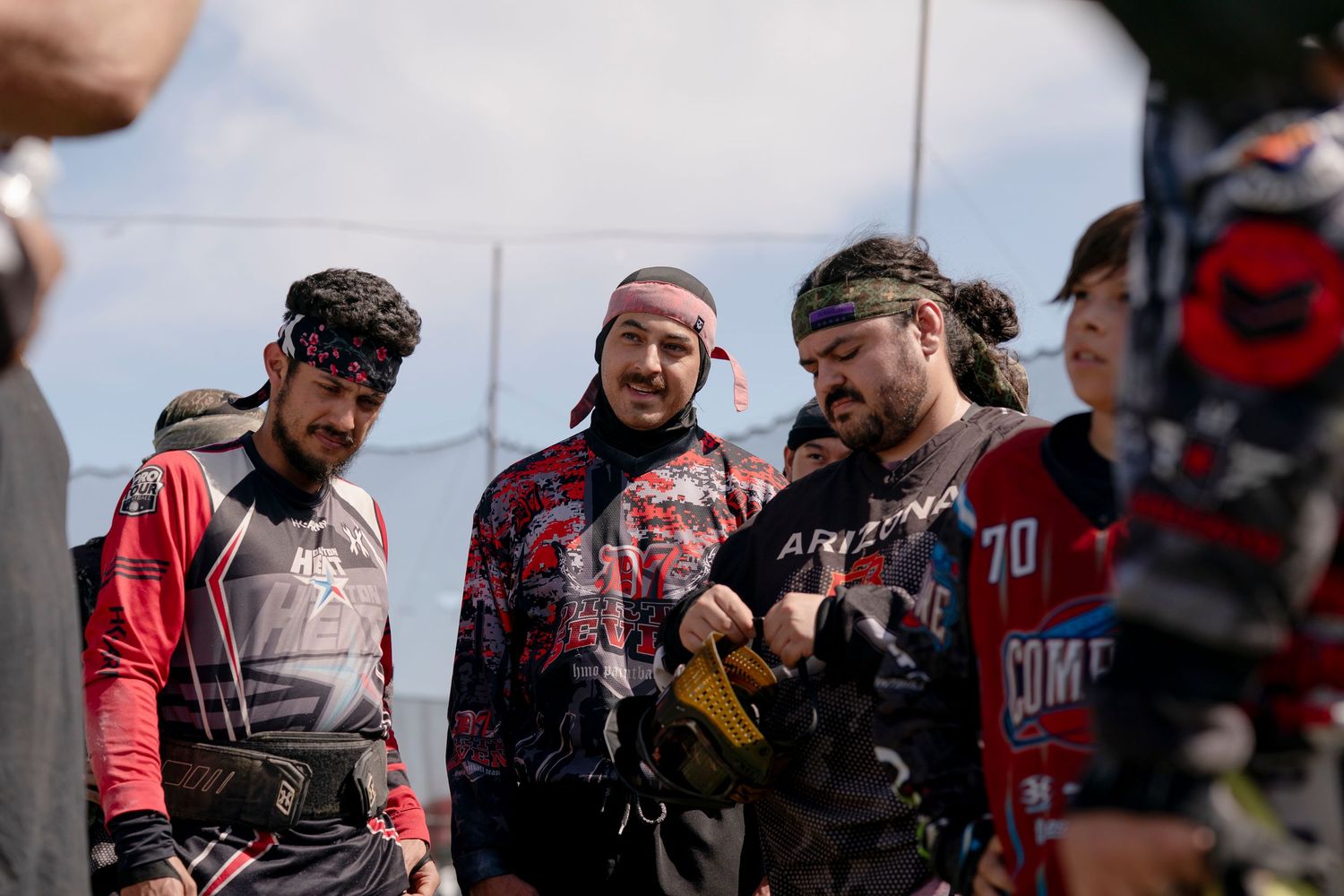 Group of paintball players huddled together in discussion during game break.