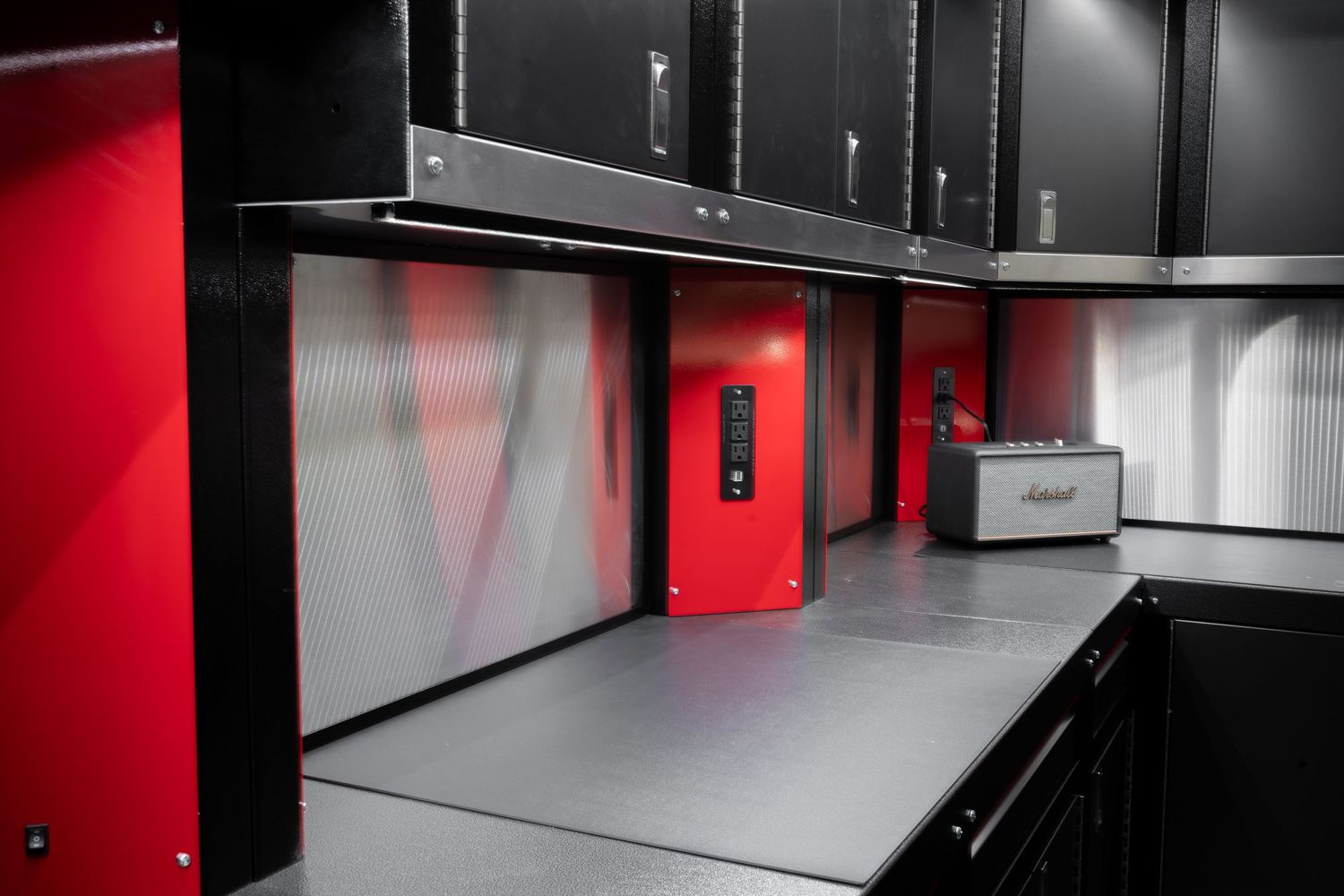 Modern black and red garage storage system with sleek metal cabinets and countertops.