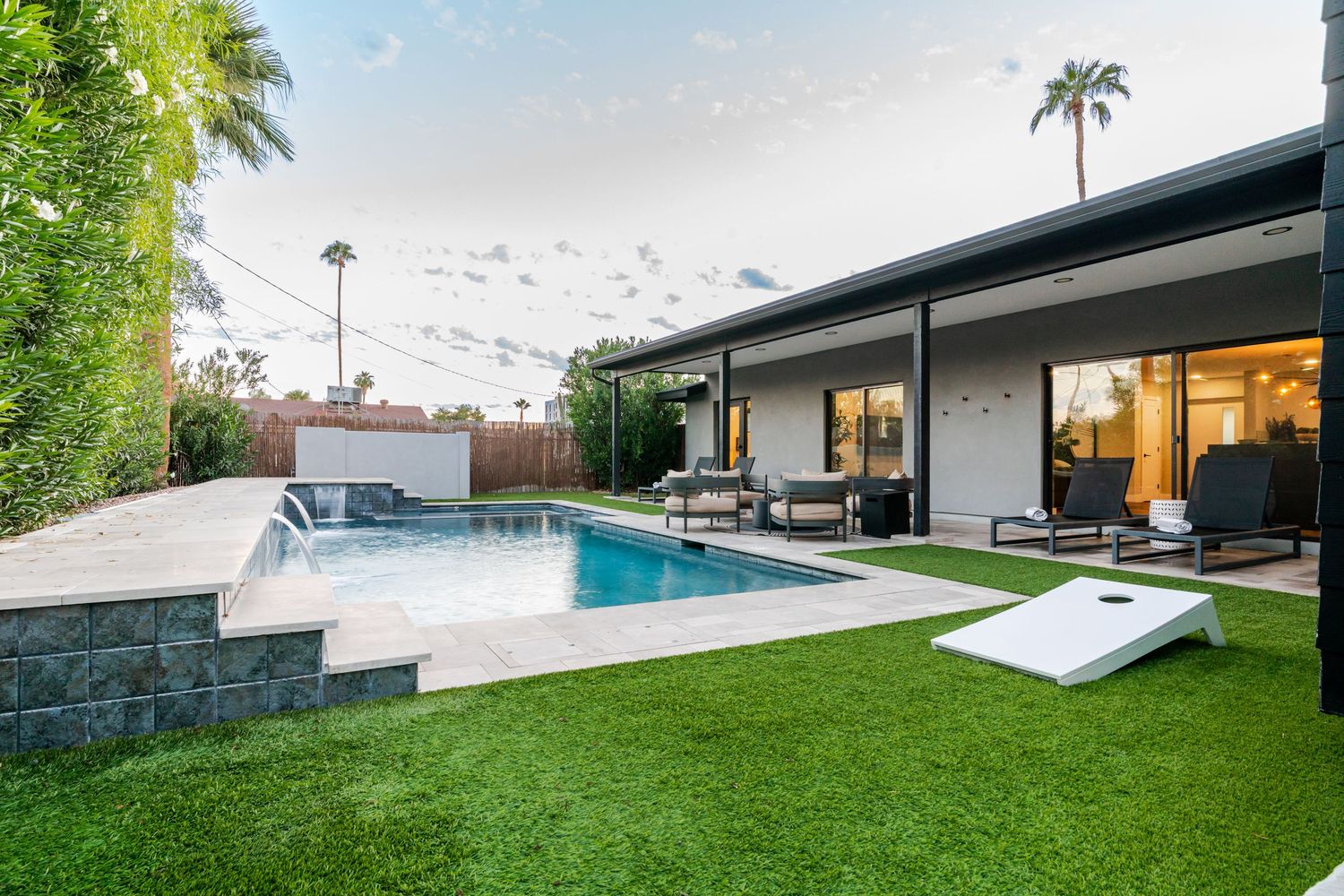 Modern backyard with sleek pool design, green lawn, and contemporary architecture features a minimalist aesthetic.